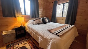 A cozy bedroom with a bed, a nightstand, a lamp, and a rug. - The Cozy Cabin: Mountain Escape at Snowshoe, WV (Slaty Fork)