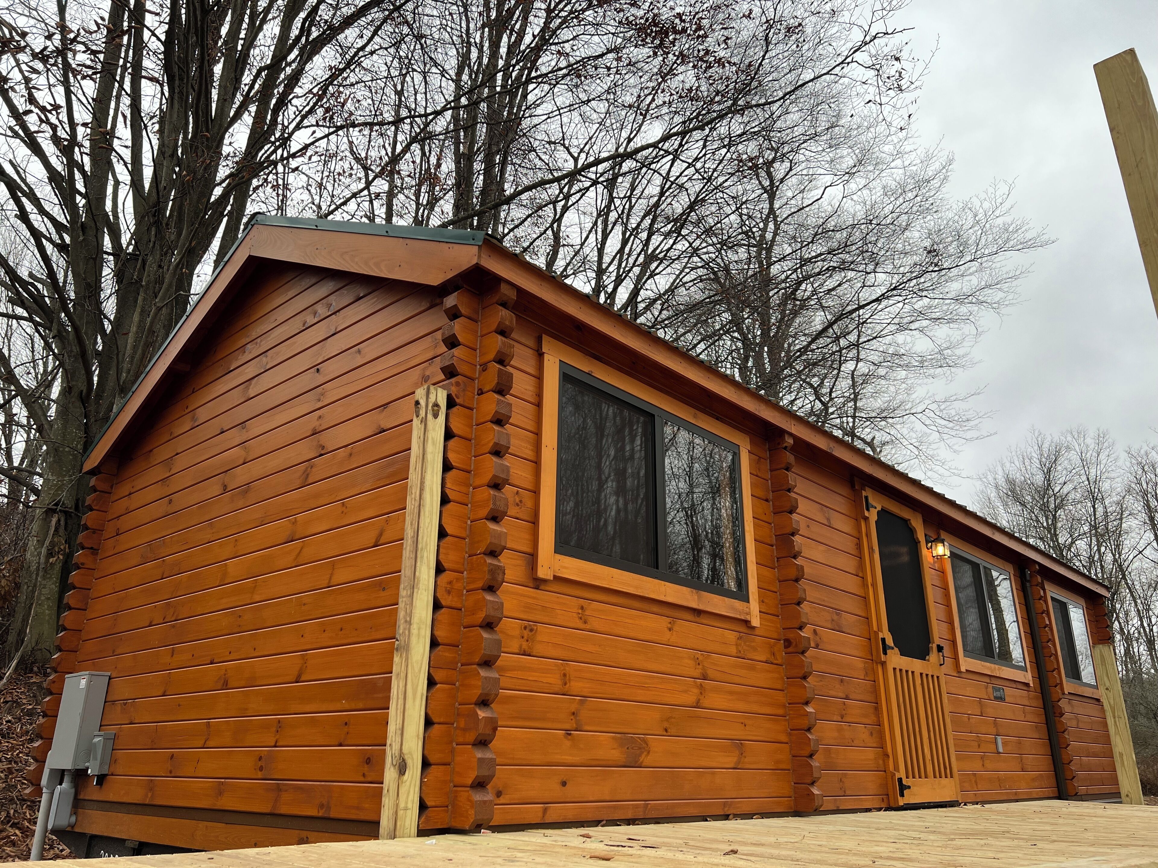 A log cabin with a gabled roof, large windows, and a wooden door.