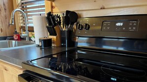A kitchen with a black stove, a sink, and wooden cabinets. - The Cozy Cabin: Mountain Escape at Snowshoe, WV (Slaty Fork)