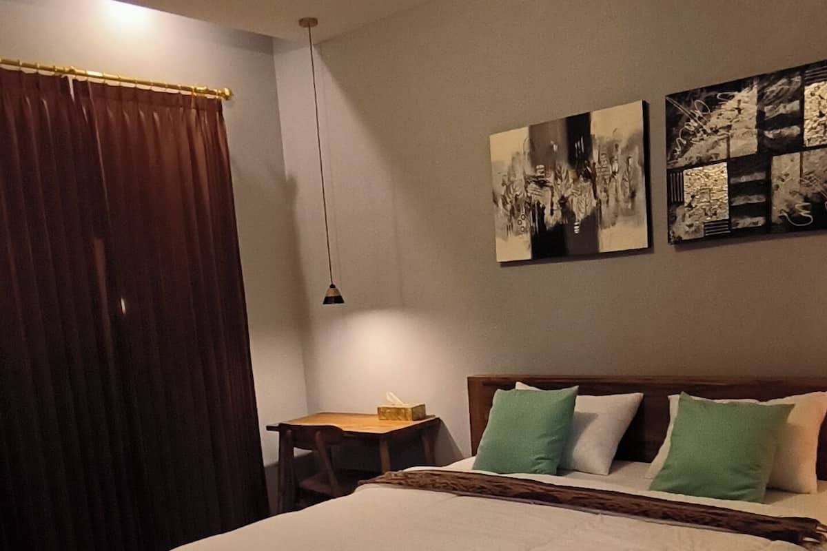 A bedroom with a large bed, a nightstand, a lamp, and two wall art pieces.