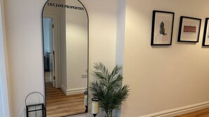 A hallway with a mirror, a potted plant, and framed pictures on the wall. - Modern Leeds Central Stay -2 min walk from station (Leeds)