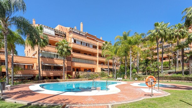 A multi-story hotel with a swimming pool surrounded by palm trees and a brick pathway. - Genteel Home Costa Nagüeles (Marbella)