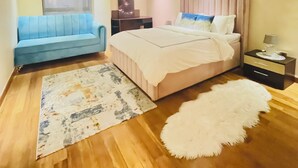 Ein Schlafzimmer mit einem Bett, einem blauen Sofa, einem Nachttisch und einem Teppich.