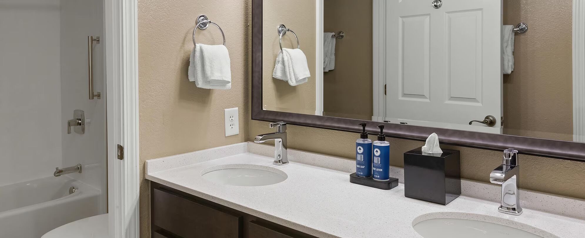 A bathroom with two sinks, a mirror, and a towel rack.