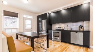 A modern kitchen with black cabinets, stainless steel appliances, and a wooden floor. - HOMA-Comfort&Style-2BR-Spacious-Natural Light-FeelHome-A/C-SelfCheckIn-Metro (Montréal)