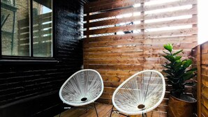 A wooden floor with two white wicker chairs and a potted plant. - HOMA-Comfort&Style-2BR-Spacious-Natural Light-FeelHome-A/C-SelfCheckIn-Metro (Montréal)
