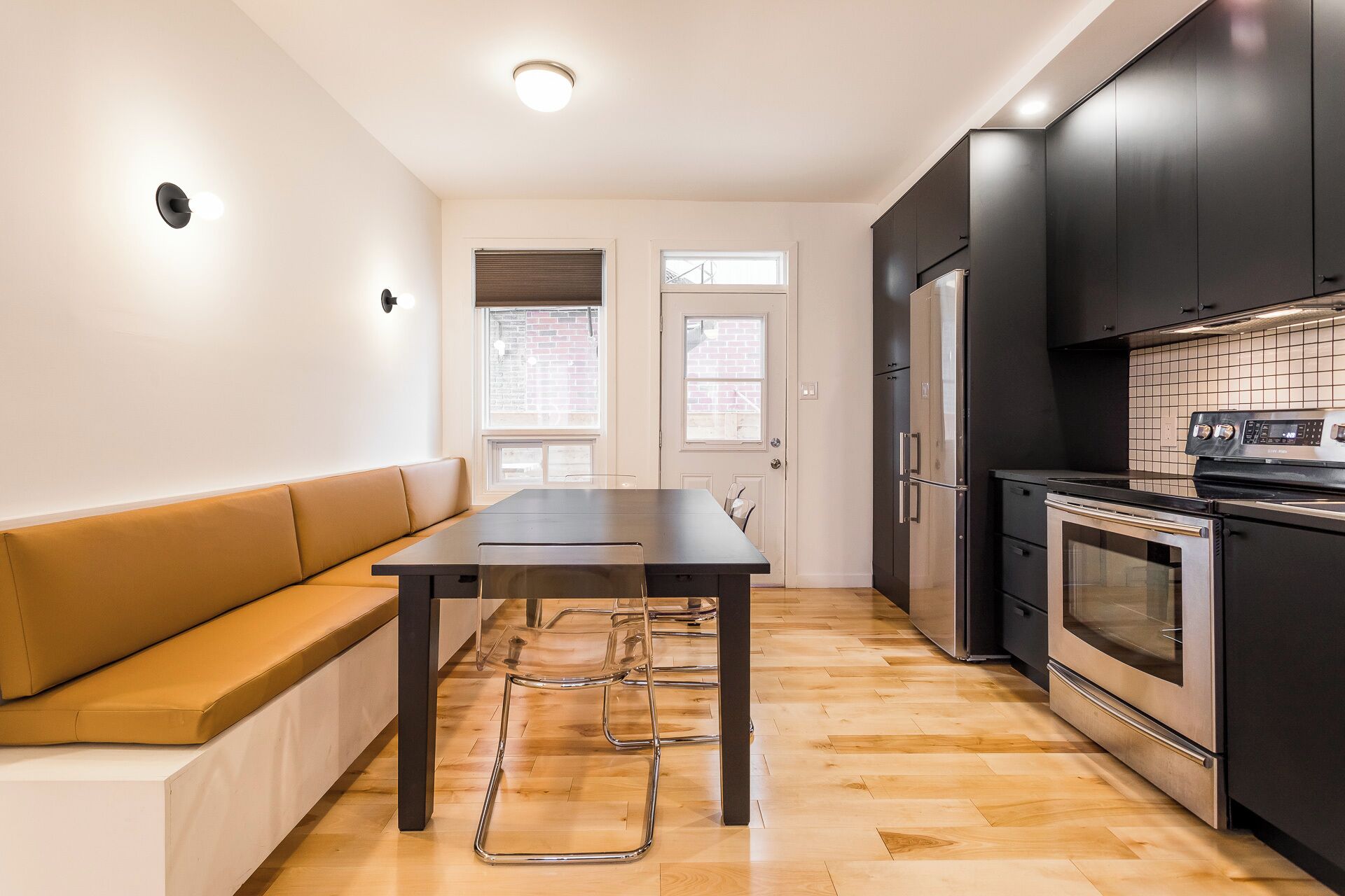 Une cuisine moderne avec une table à manger, des bancs et des appareils électroménagers intégrés.