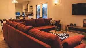 Ein modernes Wohnzimmer mit einer Eckcouch, einem Flachbildfernseher und einem Holztisch.