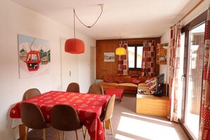 Una sala de estar acogedora con comedor, paredes de madera, un conjunto de sofás y una televisión.