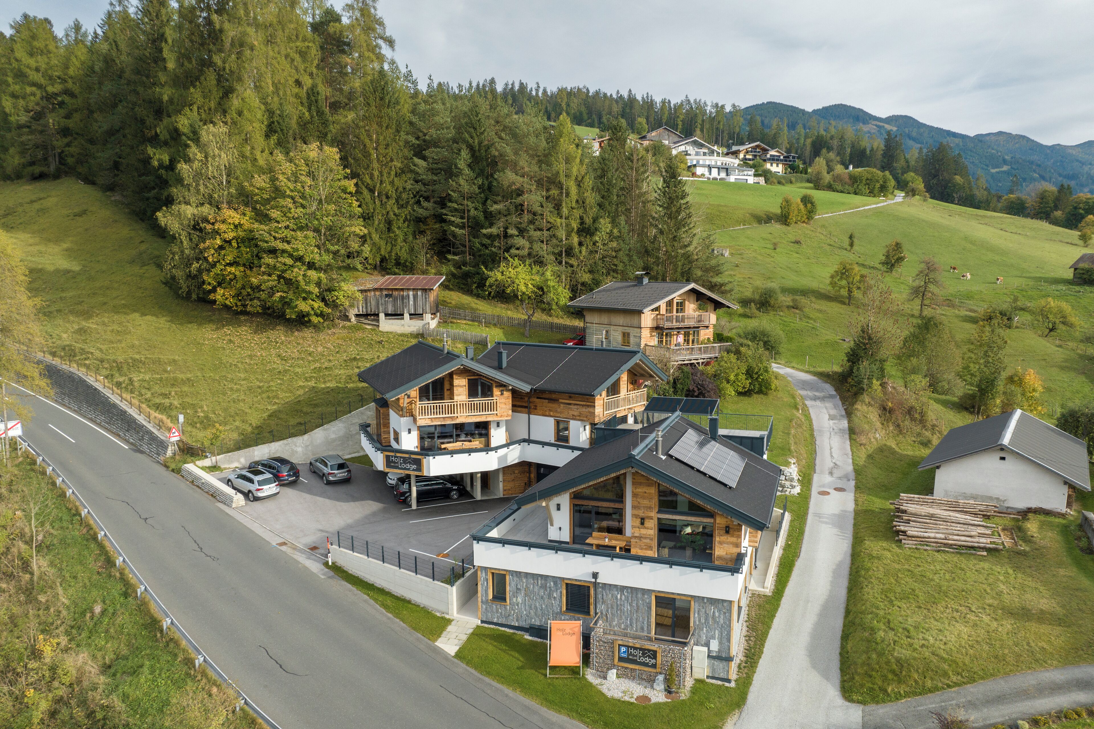 Ein modernes Hotel mit mehreren Gebäuden, einem Parkplatz und einer Straße.
