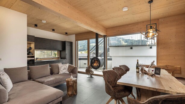 Un interior moderno con techo de madera, un sofá, una mesa de comedor con sillas y una chimenea.
