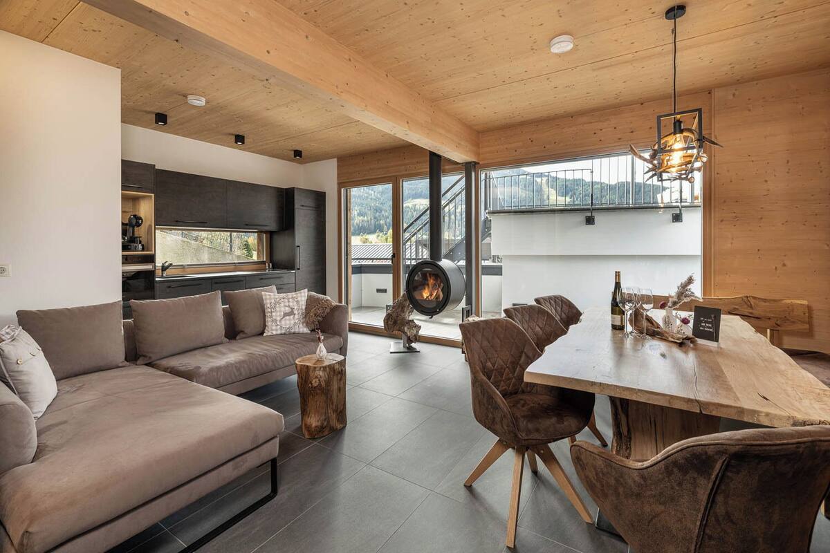 A modern interior with a wooden ceiling, a sofa, a dining table with chairs, and a fireplace.