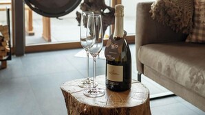 Un salón acogedor con una estufa de leña, una botella de vino y dos copas sobre un tocón de árbol.