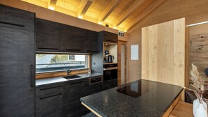 Una cocina moderna con muebles oscuros, encimera de granito y vistas al exterior.