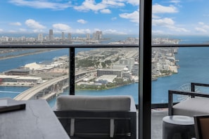 Habitación de hotel en un rascacielos con vista al horizonte urbano, un ventanal grande y vistas al agua y un puente.