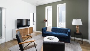 A modern living room with a flat-screen TV, a blue sofa, a coffee table, and a lamp.