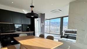 Una cocina moderna con armarios oscuros, una mesa de comedor de madera y vistas a la ciudad a través de amplios ventanales.