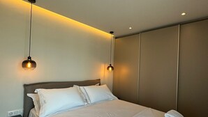 Una habitación de hotel moderna con una cama grande, dos mesitas de noche y un armario.