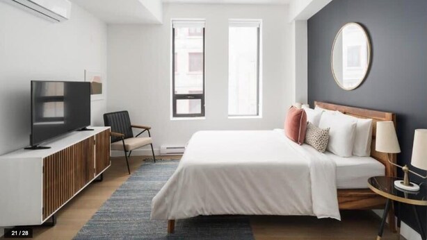 A modern bedroom with a bed, bedside tables, a TV, and a window. - Bakan- Studio Downtown/Old Montreal (Montréal)