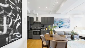 Una cocina moderna con armarios grises, una campana de acero inoxidable y un comedor con mesa y sillas de madera.