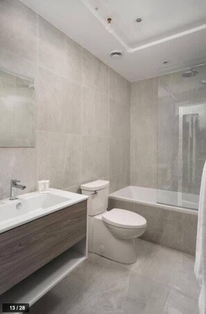 Une salle de bain moderne dotée d’une grande baignoire, de toilettes séparées et d’un meuble-lavabo avec un miroir.