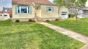 A single-story house with a front porch, a small front yard, and a tree. - Stumble-In Guest House- Downtown Location (Hermann)