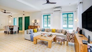 Amplia sala de estar con sofá, mesa de centro y mueble para la televisión, con piso estampado y ventanas grandes.