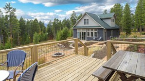 Une terrasse avec du mobilier d’extérieur, une maison dotée d’un toit végétalisé et un paysage boisé en arrière-plan.