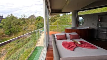 Un dormitorio moderno con una cama grande, un escritorio pequeño y vistas a un paisaje verde.