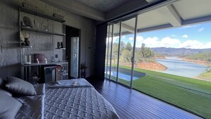 Una camera da letto con un letto grande, una scrivania e vista su un lago e montagne.