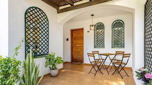 A patio with a wooden table and chairs, potted plants, and a door. - Casa Chic de Ensueño, BBQ Azotea, 9 Piscinas, Golf (Marbella)