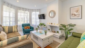 A modern living room with a sofa, armchair, coffee table, fireplace, and a television. - Casa Chic de Ensueño, BBQ Azotea, 9 Piscinas, Golf (Marbella)