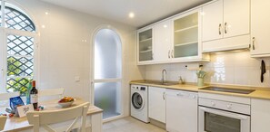 Enjoy cooking in this well-equipped kitchen with appliances, a sink, and a window with a decorative lattice design.