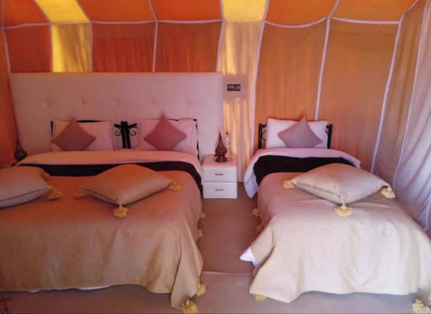 Een kamer met twee bedden, elk met hoofdeinde, nachtkastje en lamp.