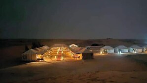 A desert resort with multiple yurts illuminated at night, connected by a central pathway.