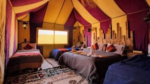 A tent-style room with two beds, a large window, and a decorative wall.