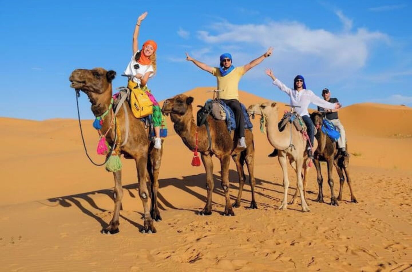 A group of people riding camels in a desert.