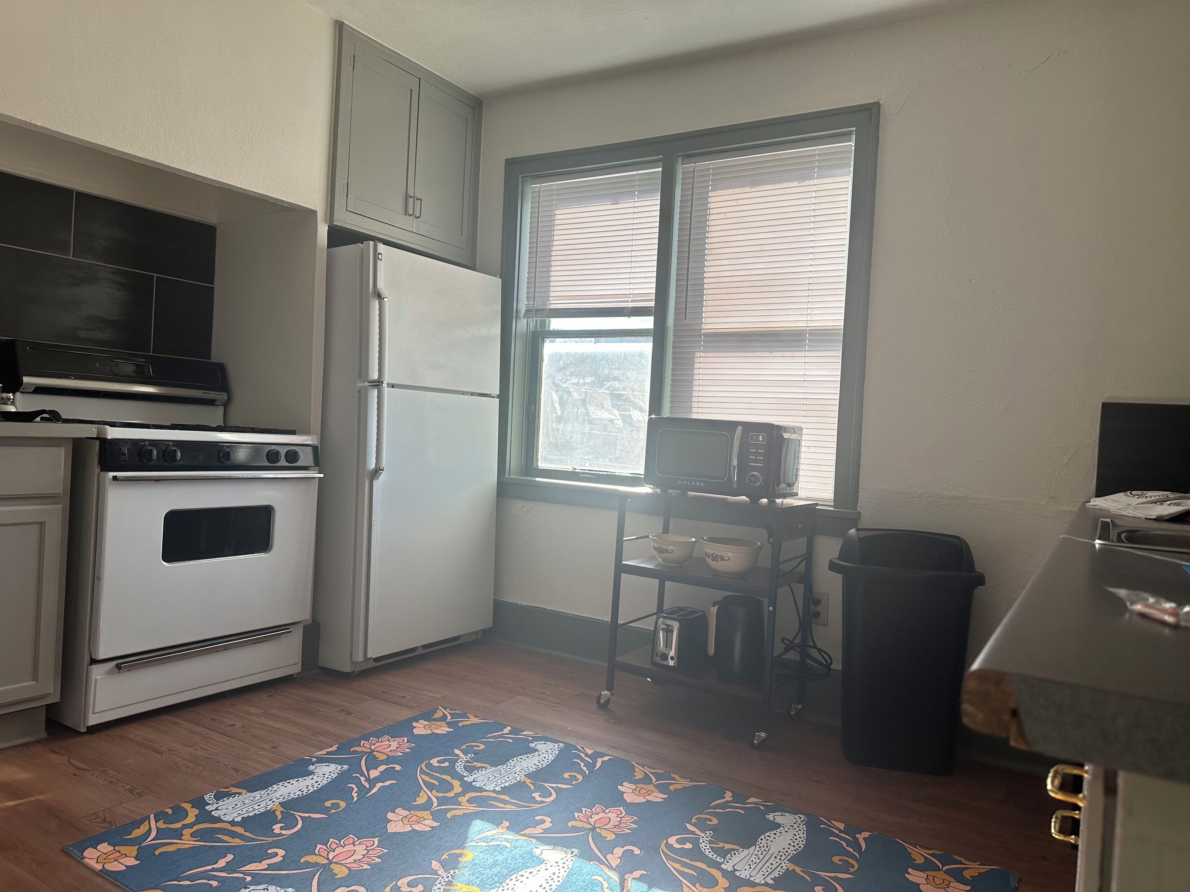 Una cocina compacta con estufa, horno, microondas y una ventana con persianas.