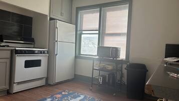 Una cocina compacta con estufa, horno, microondas y una ventana con persianas.
