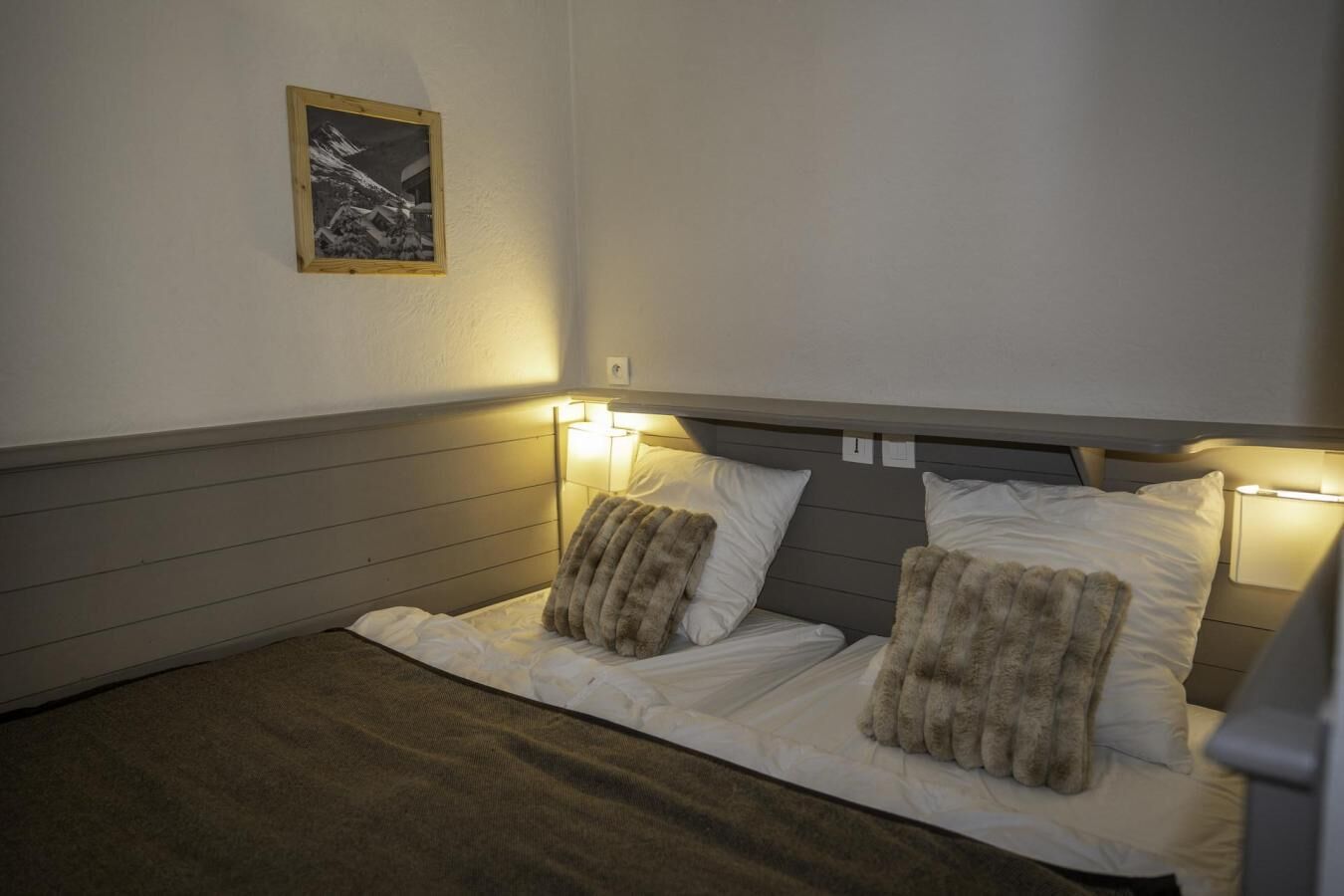 A single bed with a headboard, two pillows, and a bedside lamp.