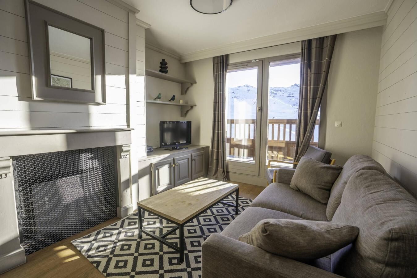 A living room with a fireplace, a sofa, a coffee table, and a TV.