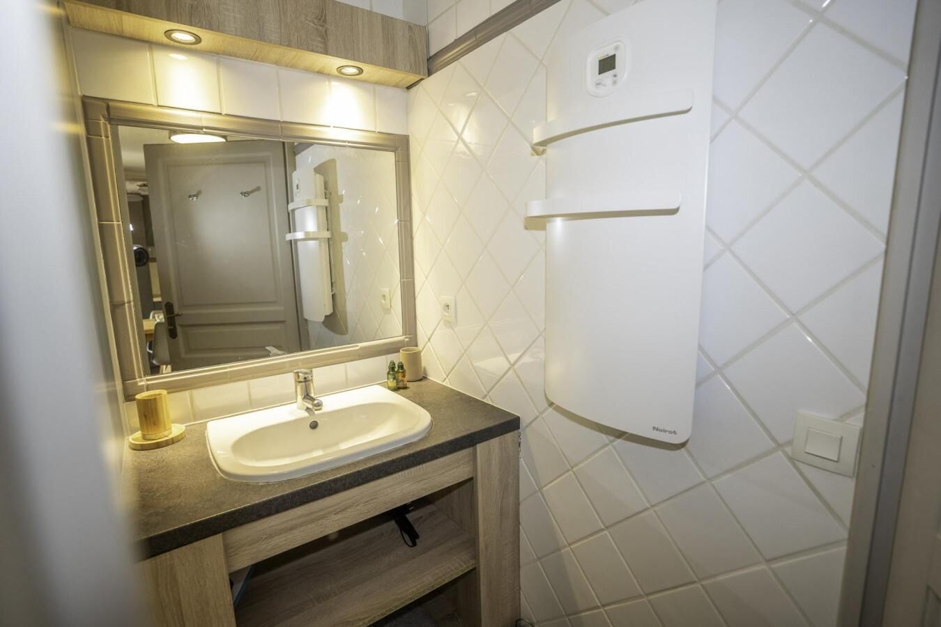Une salle de bain équipée d’un lavabo, d’un miroir et de toilettes fixées au mur.
