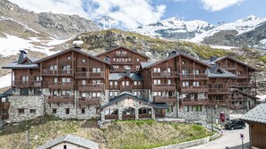 A multi-story wooden lodge with balconies, stone foundation, and a ski lift in the background. - 100m from ski slopes, 2nd floor, balcony, fireplace or stove, tv, ski locker, 44m², Val Thorens (Val Thorens)