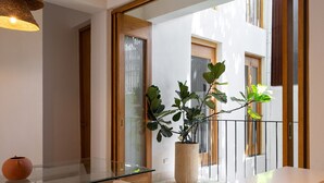 A modern interior with a glass dining table, a potted plant, and a view of the outside. - Boho Chic Oasis: 2BR + Family Room in Zona Colonial (SANTO DOMINGO)