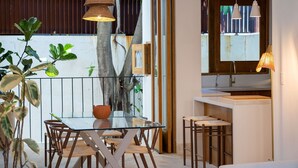 A modern kitchen with a glass dining table and chairs, a hanging light fixture, and a view of the outdoors. - Boho Chic Oasis: 2BR + Family Room in Zona Colonial (SANTO DOMINGO)