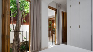 A bedroom with a large window, a tree outside, and a view of a wooden door. - Boho Chic Oasis: 2BR + Family Room in Zona Colonial (SANTO DOMINGO)