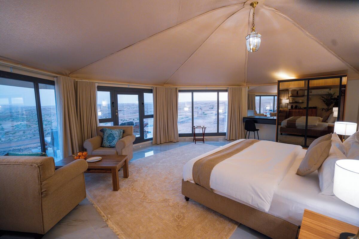 A spacious room with a large bed, a sofa, a desk, and a view of the ocean.