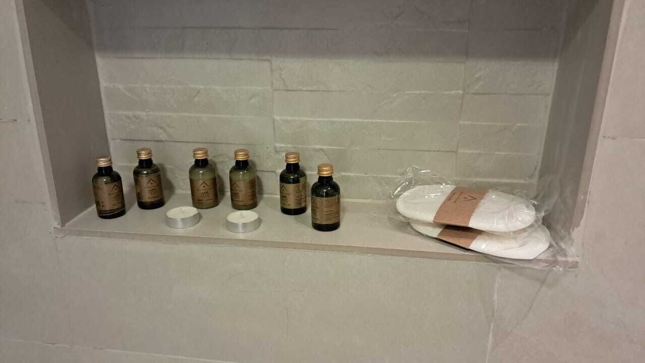 A bathroom shelf with several bottles and a package of white towels.