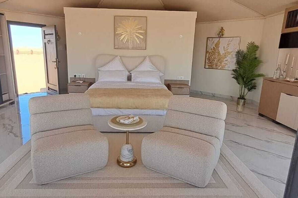 A bedroom with a bed, two armchairs, a small table, and a nightstand.