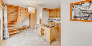 A modern kitchen with wooden cabinets, a central island, and a tiled floor.
